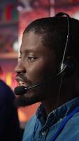Vertical Call center agent using headphones mic to talk with customers, helping regain access to accounts. Customer center worker speaking in microphone, assisting clients needing help, camera B close up video