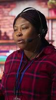 Vertical Call center agent in noisy office asking coworker to lower voice while providing guidance to customers. Customer center employee irked by loud colleague during conversation with client, camera A video