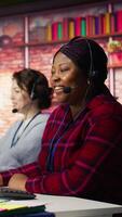 Vertical Friendly account manager in office maintaining strong client relationships to generate leads. Cheerful African american employee talking with customer, to identify new sales opportunities, camera B video