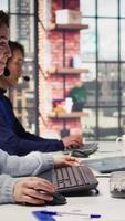 Vertical Team of call center agents tracking shipments in office, handling delivery delays. Customer center coworkers use software to locate clients packages and provide status updates, camera B video