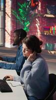 Vertical Call center agent helping customers regain access to accounts, resetting passwords. Employee in customer center workspace assisting clients needing help, providing helpful solutions, camera B video