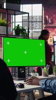 Vertical Call center agent using mockup green screen PC, providing step by step guidance to customers. Happy customer center worker using chroma key computer, diagnosing problems for clients, camera B video