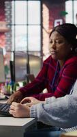 Vertical Account manager supervising work done by employee talking with customers to identify sales opportunities. Supervisor overseeing agent in office bonding with client to generate leads, camera B video