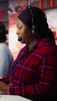Vertical Happy call center agent providing step by step guidance to customers. Smiling customer center worker at PC desk walking clients through technical solutions during call, camera B video