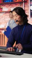 Vertical Call center senior agent providing step by step guidance to help customers using AI. Customer center worker at PC desk walking clients through technical solutions using artificial intelligence video