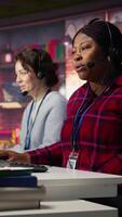 Vertical Call center agent in noisy office asking coworker to lower voice while providing guidance to customers. Customer center employee irked by loud colleague during conversation with client, camera B video