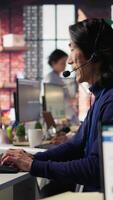 vertical técnico Apoio, suporte especialista dentro ligar Centro escritório solução de problemas cliente conectividade questão através degrau de degrau orientação usando fone de ouvido e computador posto de trabalho, Câmera b video