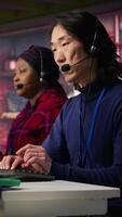 Vertical Customer center employee gesturing loud Asian senior agent to quiet down while working African american woman working in call center worker upset by noises in office made by colleague, camera B video