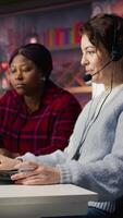 Vertical Call center team leader going over paperwork files next to colleague at PC desk. Customer support manager explaining company documentation to intern accommodating with job, camera B video