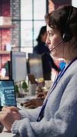 Vertical Worker providing live chat support, typing on keyboard, using AI chatbot to handle clients complaints. Call center agent dealing with unsatisfied customers using artificial intelligence LLM, camera B video