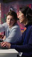Vertical Call center team leader supervising agent helping customers regain access to accounts and devices. Customer center manager overseeing intern assisting clients needing help resetting password, camera B video