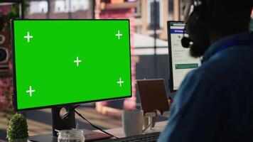 Technical support specialist in call center office doing troubleshooting using green screen computer. IT worker fixing customer connectivity issues using chroma key mockup PC, camera A video