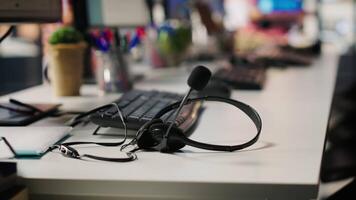 Audio equipment headset with mic used in customer support job workspace, close up. Headphones with microphone on call center company office desk used by workers to discuss with customers video