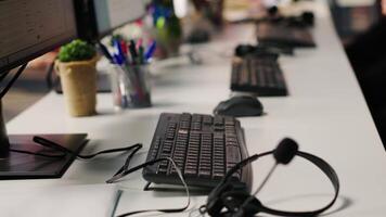 CSM system interfaces on computer monitors in empty customer service workplace and call center audio headsets. Customer service management software UI on PC displays and headphones with mic on desk video