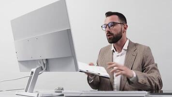 Confident Business man in formal suit holds a videoconference at his computer and reprimands a team of employees for declining revenue. Shows growth chart on paper. Online project or presentation video