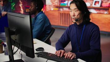Joyous technical support senior agent in call center office doing troubleshooting. Jolly experienced Asian IT worker fixing customer connectivity issues using computer, camera B video