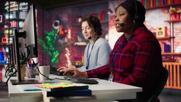 Customer center employee gesturing loud colleague to quiet down during conversation with client. Call center worker upset by noises in office while talking to customers using headphones mic, camera B video