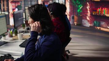 Technical support specialist in call center office doing troubleshooting, speaking in headset mic. IT worker fixing customer connectivity issue, talking in headphones microphone, camera B close up video