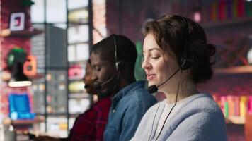 Call center agent handling inbound calls, assisting customers with inquiries, updating account records and meeting performance metrics in office environment, camera A close up video