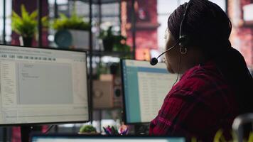 IT support specialist at PC in office helping customers during call, troubleshooting errors. Tech support agent at desk looking at computer monitor, fixing technical issues for clients, camera A video