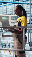 Vertical Portrait of happy engineer in smart photovoltaics factory looking at system performance metrics. Cheerful worker in solar panels plant tracking energy production through IoT sensors, camera A video