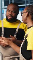 Vertical System administrators in smart factory collecting and analyzing data. Coworkers doing brainstorming, using tracking software in industrial plant equipped with advanced sensors, camera A close up video