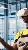 Vertical Engineer wearing VR headset in smart factory looking at collected data to do optimizations. Technicians using virtual reality in industry 4.0 industrial plant equipped with sensors, camera A video