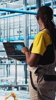 Vertical Engineers in industry 4.0 industrial plant controlling automated machinery using augmented reality. Technician in smart factory managing robotic arms and conveyor belts using AI technology, camera A video