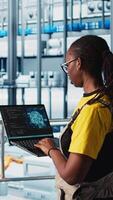 Vertical Engineer in smart factory using augmented reality to collect data on laptop. Professional on platform in industry 4.0 industrial plant equipped with sensors using AI technology, camera A video
