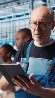 Vertical Senior engineer in smart factory rigorously testing automated systems to ensure reliability and safety. Technician identifying bottlenecks and optimizing equipment based on sensors data, camera A video