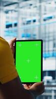 Vertical Smart factory expert using green screen tablet to test automated systems and ensure reliability. Worker uses chroma key device to identify bottlenecks and optimize gear based on sensors data, camera A video