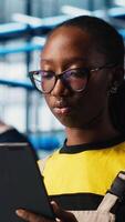 Vertical Smart factory engineer implements automated workflows and control systems using tablet, computerizing manual operations. Industry 4.0 worker integrates sensors into production using device, camera A video