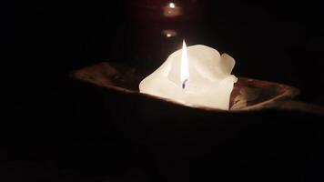 The flame of a burning candle in the dark. A candle burns on a wooden stand on the table. video