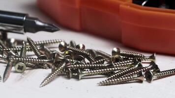 screws on a wooden table against a background of a screwdriver and nozzles set. screws close-up. video