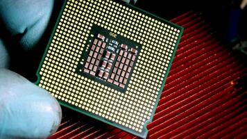 Close-up of a technician's gloved hand holding a CPU above a red heat sink, emphasizing computer hardware installation. video