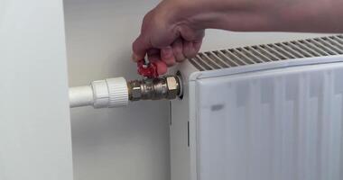 Close-up of a person adjusting a valve on a home radiator, emphasizing heating system maintenance and temperature control. video