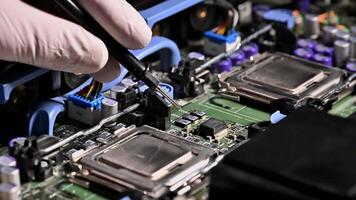 A technician wearing gloves uses a tool to inspect components on a computer motherboard, highlighting computer repair and electronics work. video