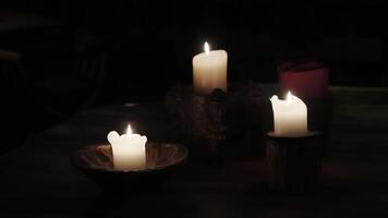 Three burning candles in the dark. Three candles are burning on a wooden stand on the table. video