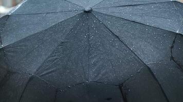 Close-up of a black umbrella covered in raindrops during a rainy day, highlighting weather protection and the ambiance of rainfall. video