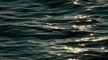 Close-up of sunlight reflecting off gentle waves on the water's surface, highlighting the serene and calming effect of natural light on water. video