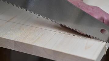 Close-up of a person using a hand saw to cut through a wood plank, emphasizing woodworking, DIY projects, and craftsmanship. video