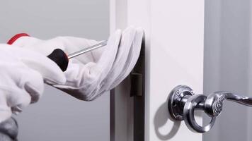 Close-up of a person using a screwdriver to install a door lock, emphasizing home security, maintenance, and DIY tasks. video