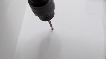Close-up of a power drill making a hole in a white wall, highlighting home improvement, DIY projects, and construction tasks. video
