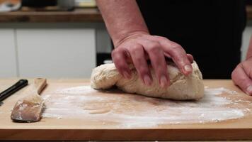 Close-up of a hand kneading dough on a wooden board, capturing the process of preparing homemade bread or pastries in the kitchen. video