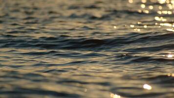 The blue surface of the ocean with gentle ripples on the surface and the refraction of light at sunset. video