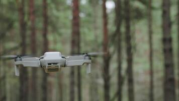 A modern drone flies in the forest. A small drone in the air against a forest landscape. video