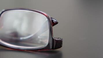 Front view of reading glasses with brown frames on a black office table. Close-up of spectacles. video