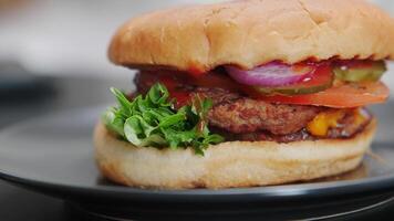 Classic cheeseburger with beef patty, pickles, cheese, tomato, onion, lettuce and ketchup on the table. video