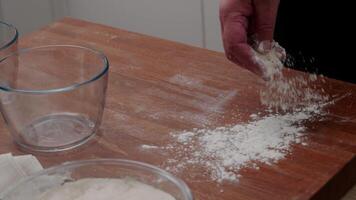 The cook's hands sprinkle flour on the table before shaping and placing the dough into the mold. the cook kneads the dough. video