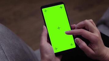 Person sitting on a couch using a cell phone with a green screen. mobile app mockup. video